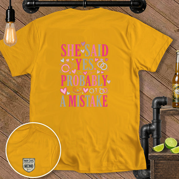 Yellow t-shirt with "SHE SAID YES PROBABLY A MISTAKE" text and small badge.