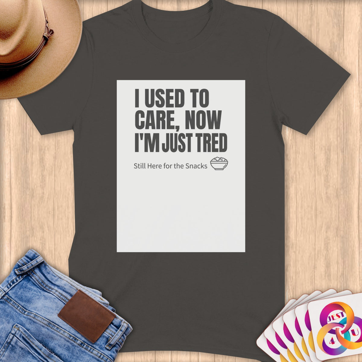 Dark grey t-shirt with text "I USED TO CARE, NOW I'M JUST TRED Still Here for the Snacks."