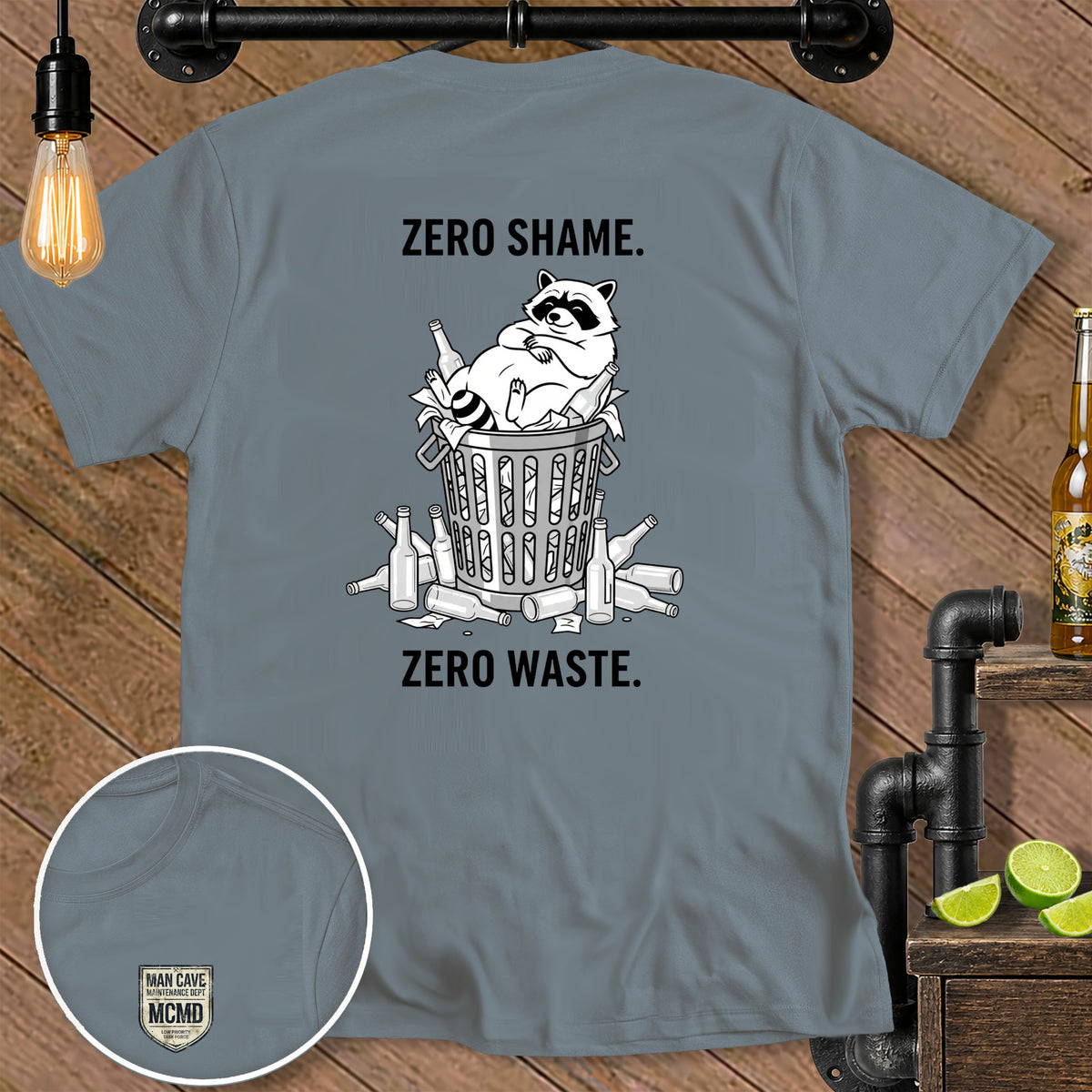 Grey t-shirt with raccoon in trash bin, text "ZERO SHAME." and "ZERO WASTE."