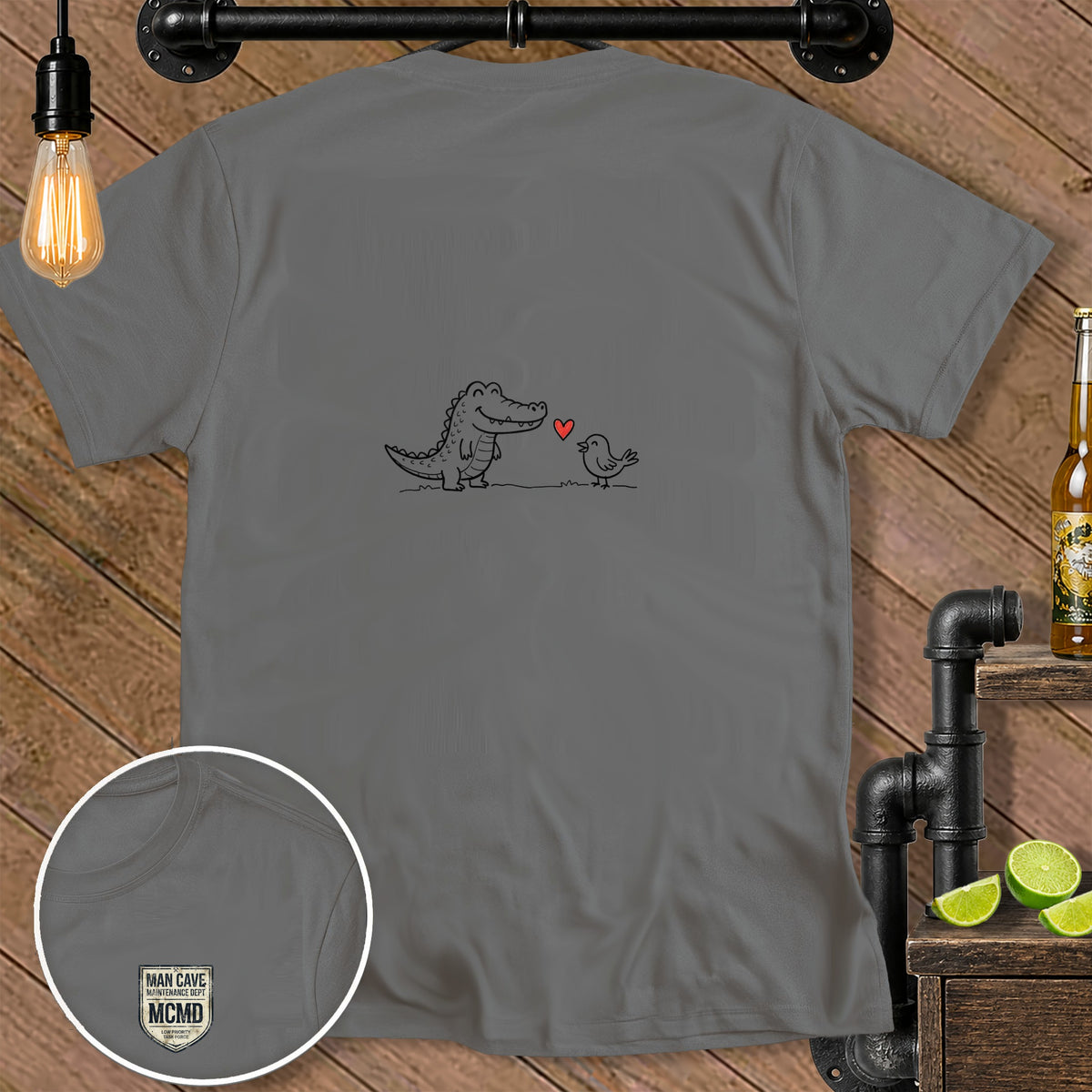 Grey t-shirt with cartoon alligator and bird illustration and "MAN CAVE MCMD" logo.
