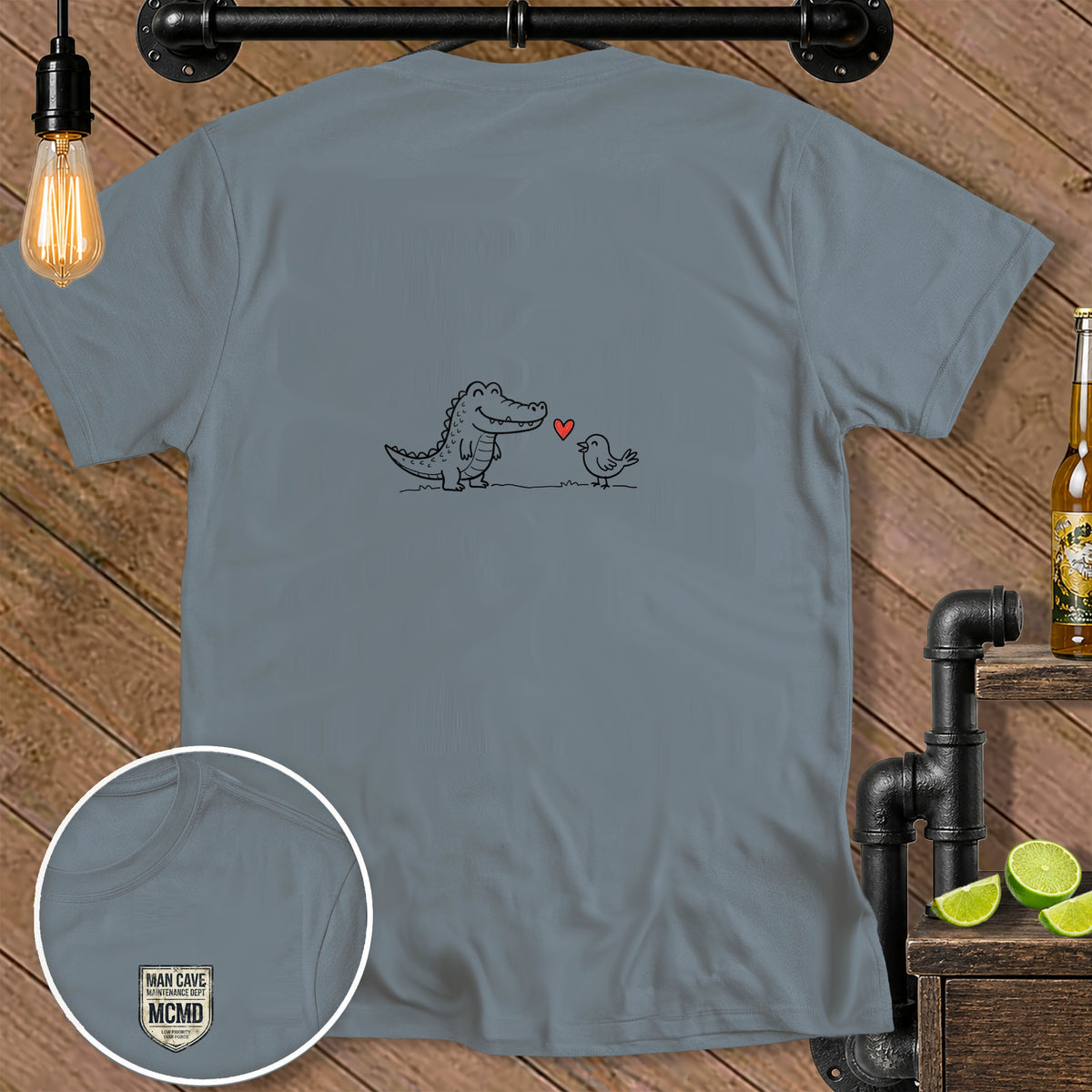 Gray t-shirt with cartoon alligator, bird, and heart graphic. Inset shows logo.