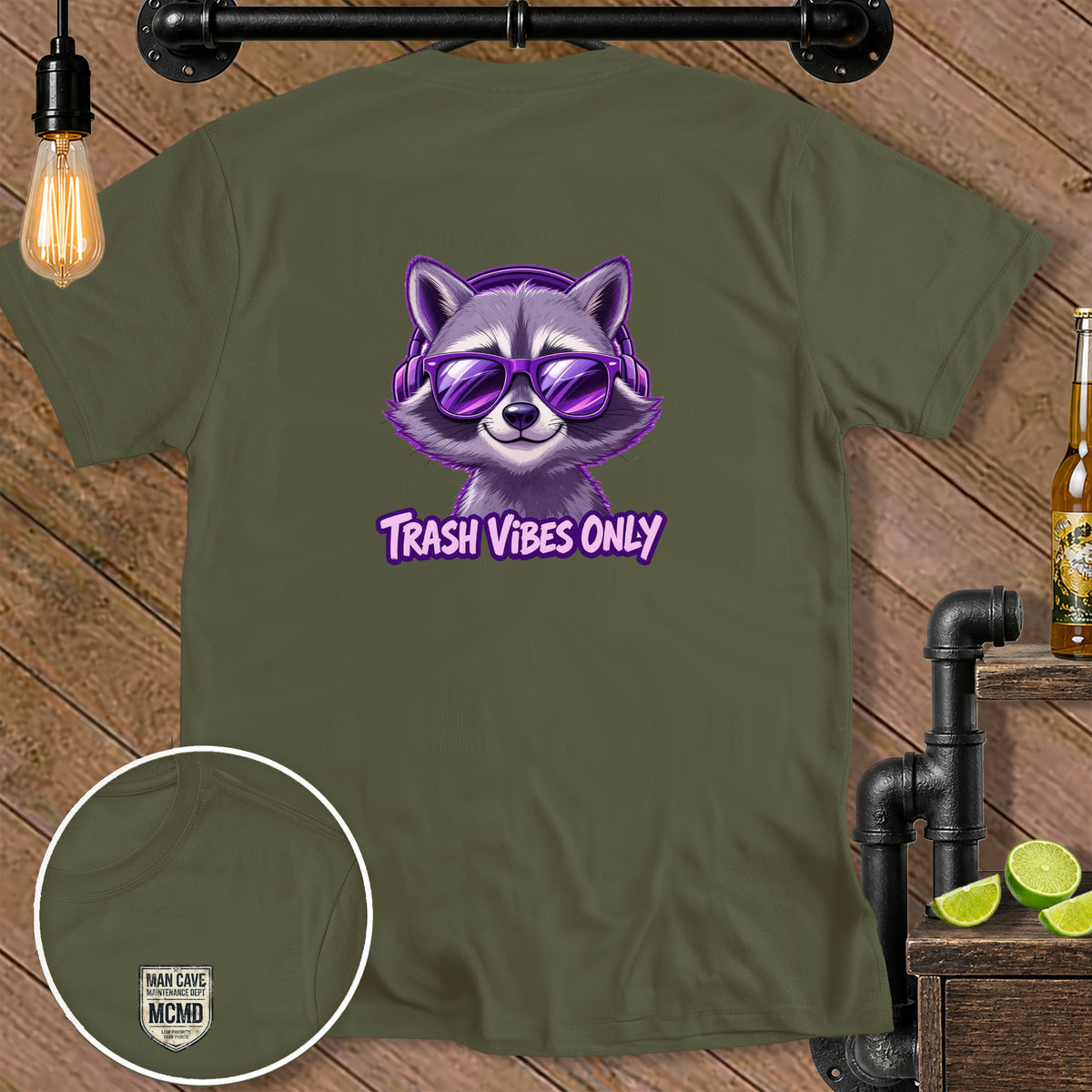 Olive t-shirt with a purple raccoon graphic wearing sunglasses and headphones and text "TRASH VIBES ONLY".