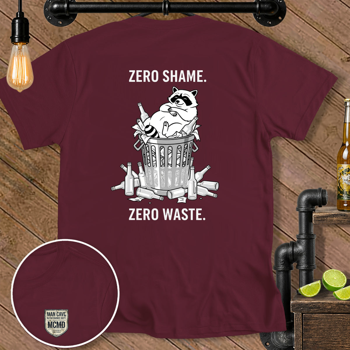 Maroon t-shirt with a raccoon in a trash can surrounded by bottles, reading "ZERO SHAME. ZERO WASTE."
