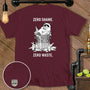 Maroon t-shirt with a raccoon in a trash can surrounded by bottles, reading "ZERO SHAME. ZERO WASTE."
