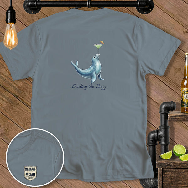 Grey t-shirt with a seal balancing a cocktail and text "Sealing the Buzz".