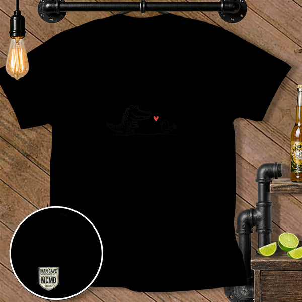 Black t-shirt with a whimsical drawing of an alligator and a bird with a red heart.