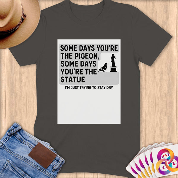 T-shirt with "Some days you're the pigeon, some days you're the statue. I'm just trying to stay dry." text.